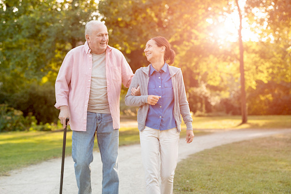 Senior Helpers caregiver walking with older client in park while providing care services
