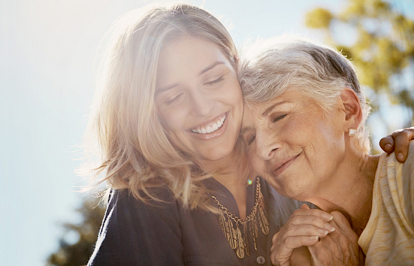 Senior care provider and elderly woman smiling and embracing