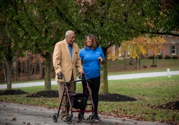 Senior Helpers franchise caregiver walking with senior client in a park